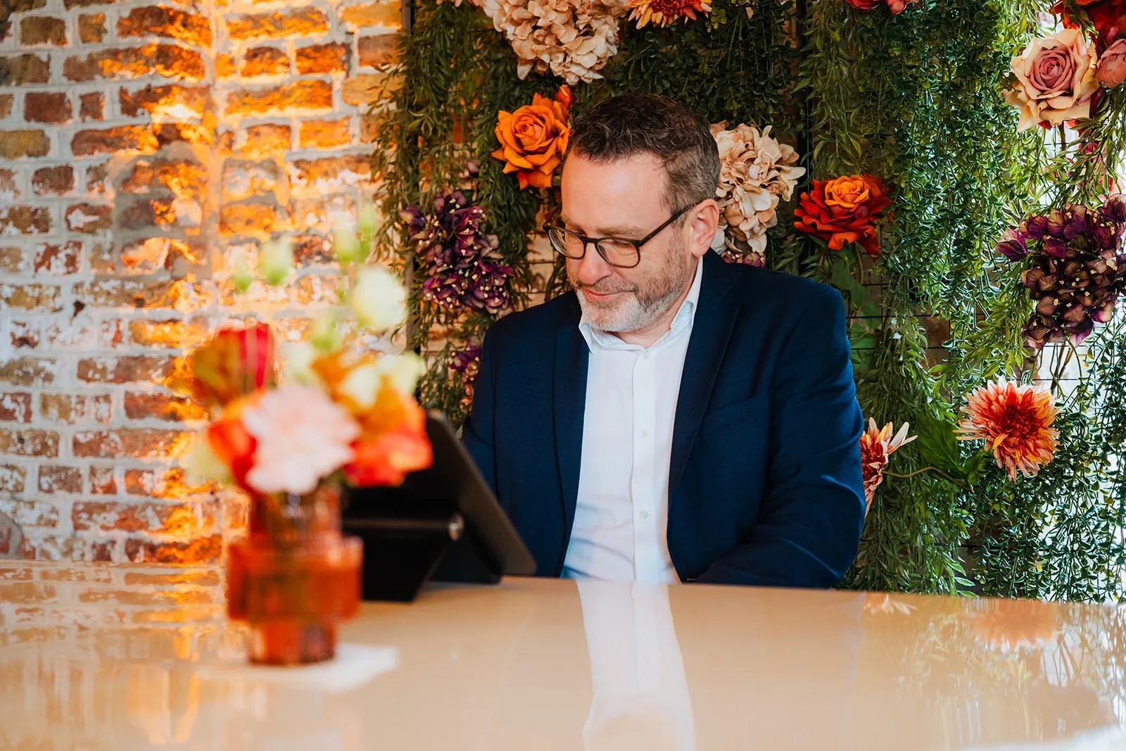 Rik Deckers glimlachend aan de witte vleugel, tussen de bloemen